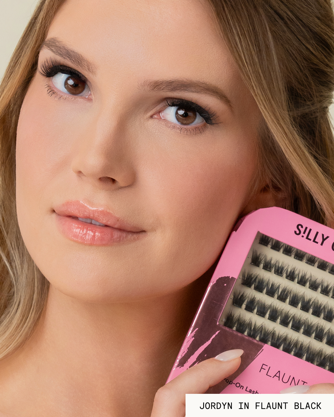 Model Jordyn holding a pink package of black Flaunt Pop-On Lashes: The Extensions Set