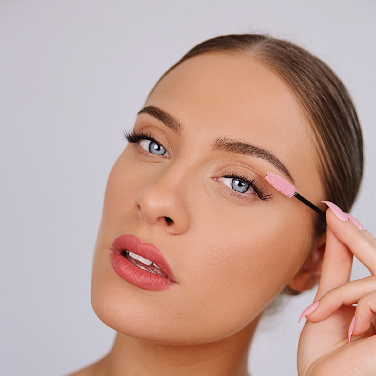 a woman brushing her fake eyelashes with an eyelash comb