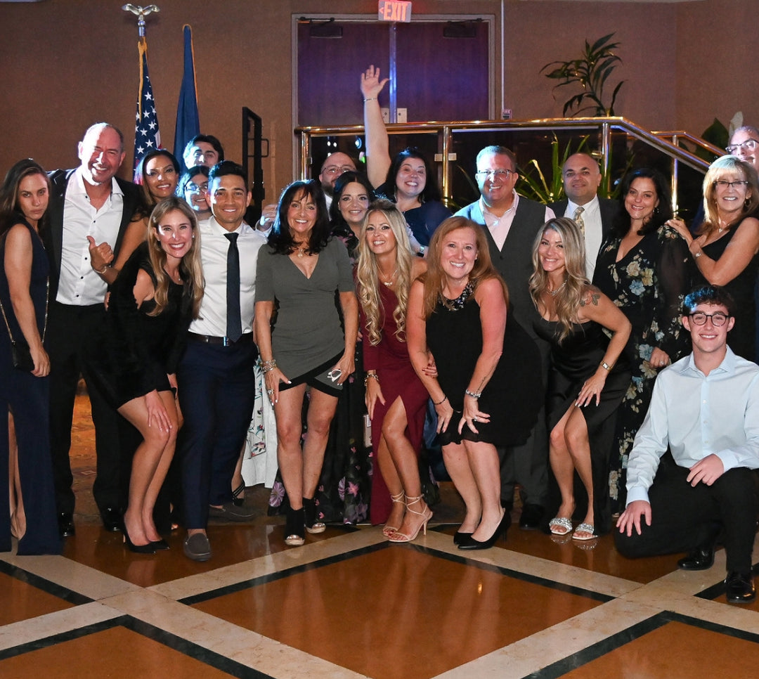 Group of people smiling and posing for a photo in an indoor setting with a decorative floor.