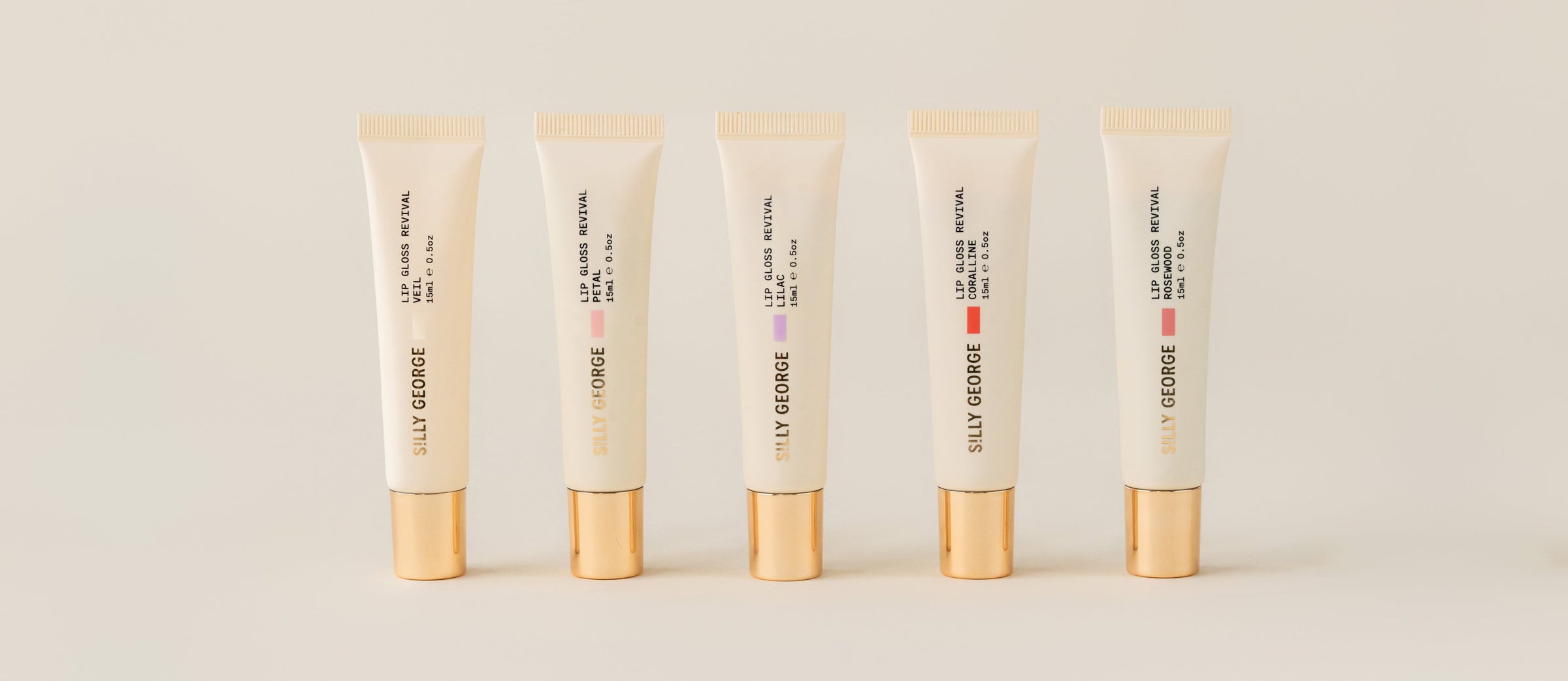 Five skincare tubes with gold caps on a beige background